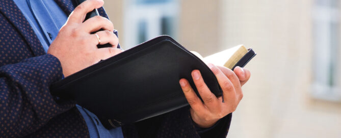 A preacher with a microphone in his hand holds a Bible and reads